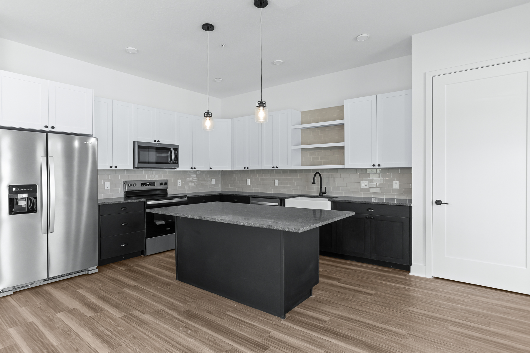 Modern kitchen with quartz island, stainless appliances, and white cabinetry